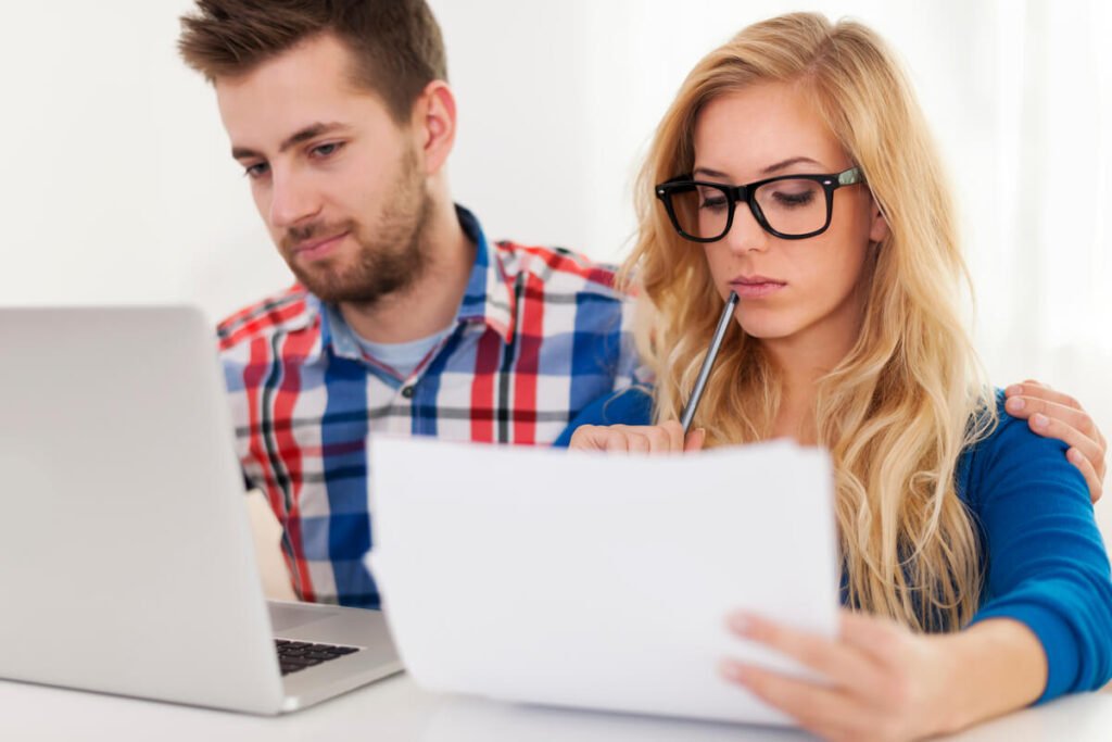 Un homme et une femme travaillant ensemble sur des documents comptables pour leur association.