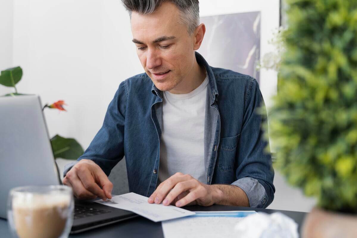 Une personne analysant ses comptes de banque sur une feuille de papier avec un surligneur.