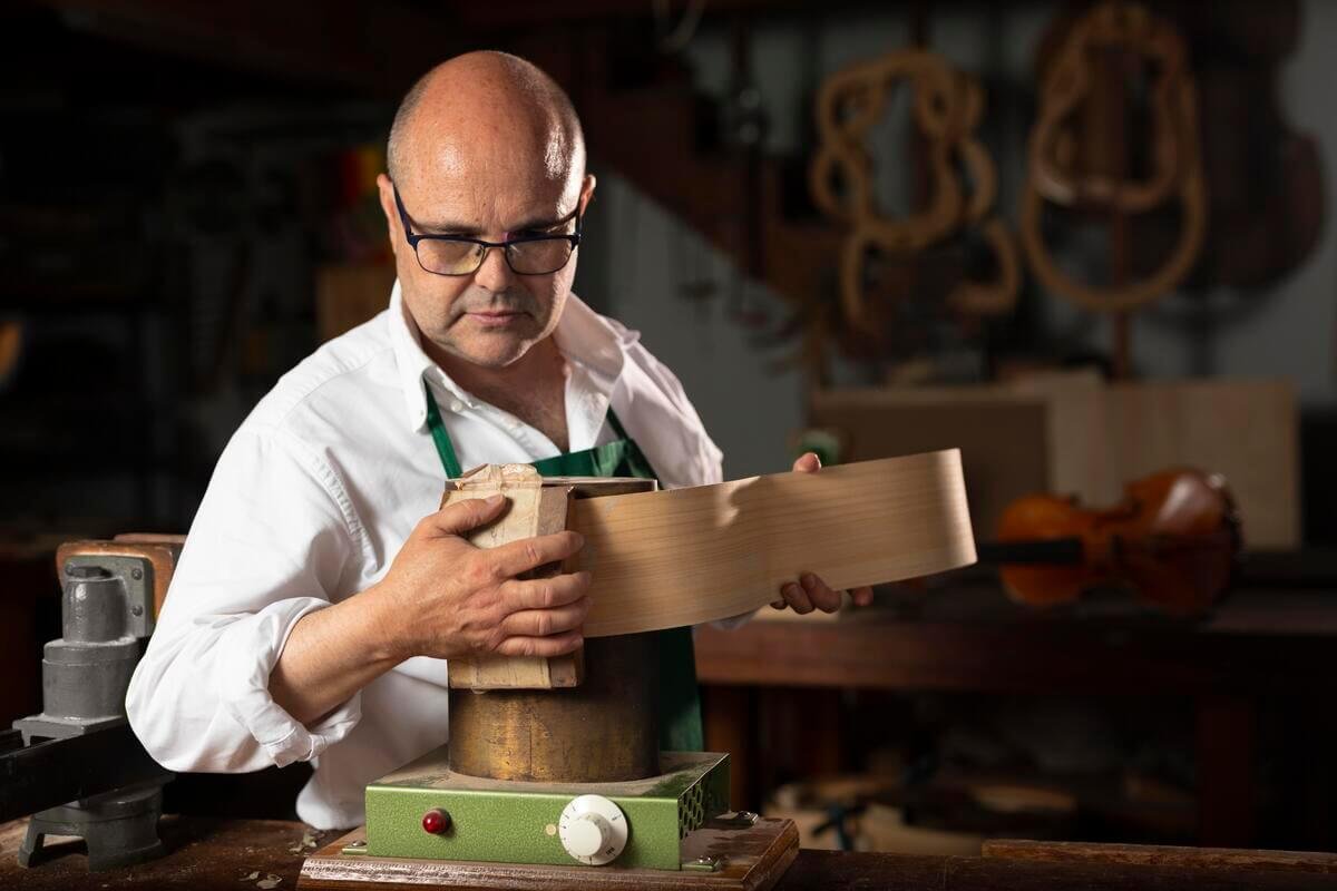 Un artisan ébéniste façonnant le bois avec passion au milieu des outils de son atelier de création.