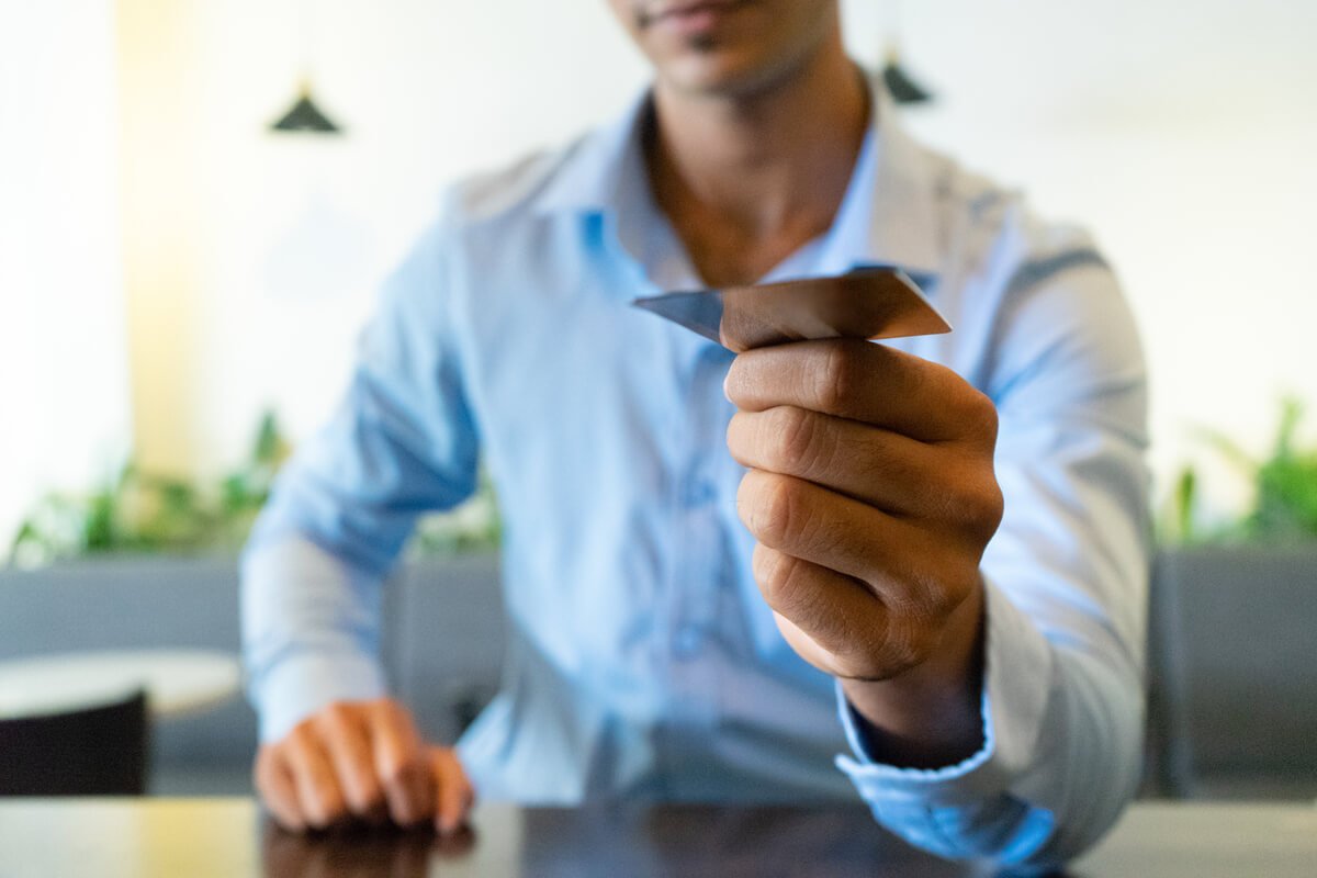Une personne tenant une carte de paiement entre ses doigts sans montrer les numéros centraux.