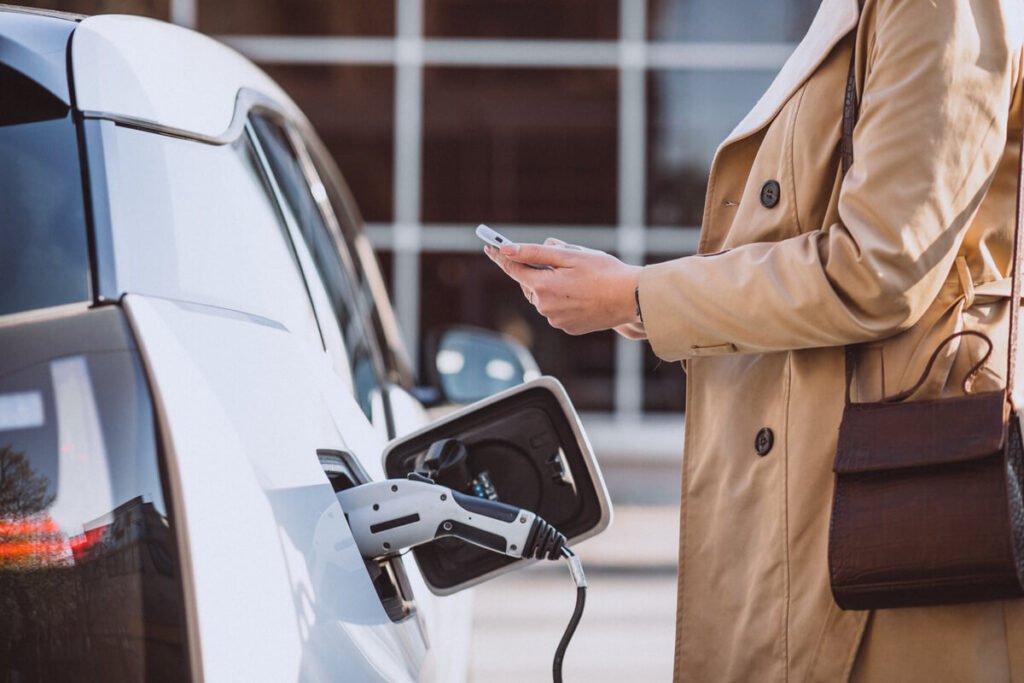 Une voiture électrique branchée sur une borne de recharge publique dans la rue.