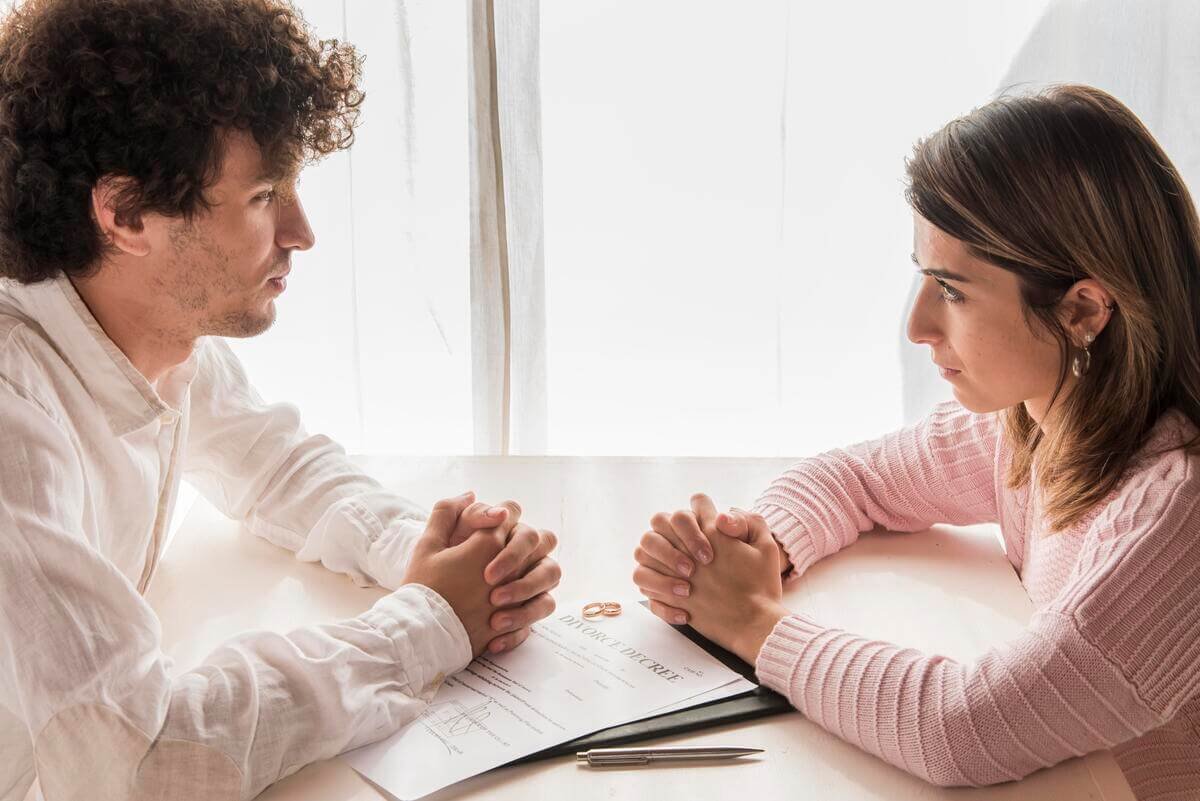 Époux signant leur convention de divorce par consentement mutuel avec leurs avocats respectifs.
