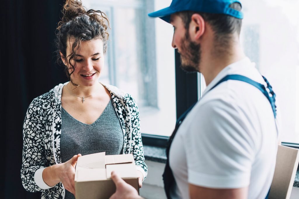 Client vérifiant le contenu d'un colis reconditionné en présence du livreur avant acceptation.